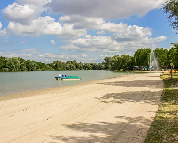 Sommerliche Idylle am Baggersee: Sandstrand, Tretboote und eine Fontäne laden zum Entspannen ein. Hier lässt sich das Leben in Karlsruhe genießen.