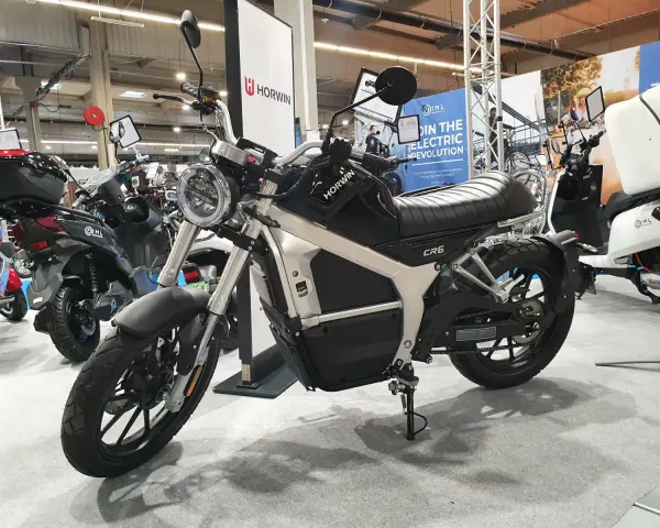 Elegancki motocykl elektryczny Horwin CR6, idealny do zdobycia prawa jazdy na motocykl. W tle inne skutery elektryczne.