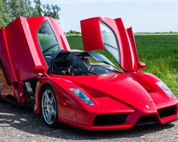 Czerwone Ferrari Enzo z otwartymi drzwiami, marzenie wielu. Zastanawiasz się, ferrari enzo ile kosztuje?