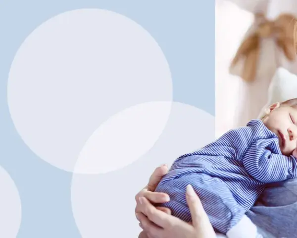 Uśmiechnięta mama tuli śpiącego noworodka w pasiastym pajacyku. Wskazówki, jak ubierać noworodka w domu.