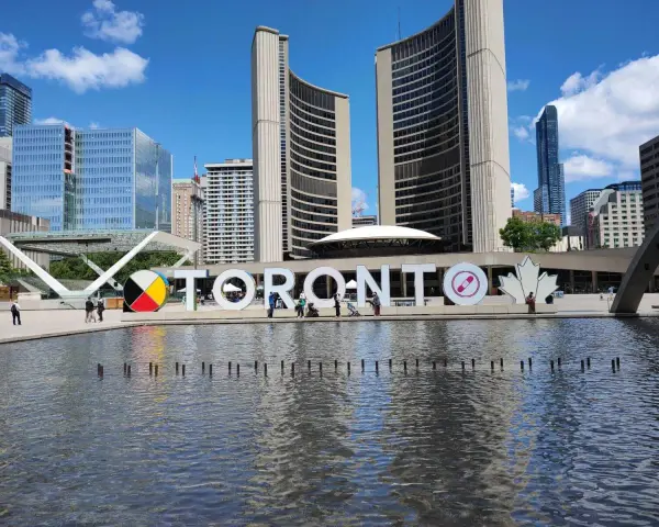 Toronto co zobaczyć: wielki napis TORONTO przed ratuszem miejskim, z fontanną i nowoczesnymi budynkami w tle.