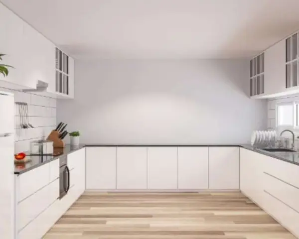 Cucina moderna con mobili bianchi e pavimento in legno. Idee per come riempire una parete vuota in cucina con mensole o quadri.