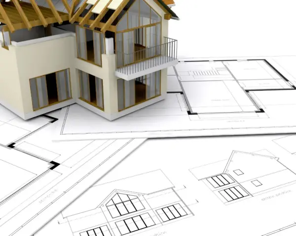 Model domu na planach architektonicznych. Zastanawiasz się, ile trwa budowa domu? To zależy od wielu czynników.