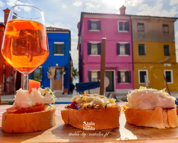 Co zjeść w Wenecji? Aperol i bruschetty na tle kolorowych domów Burano. Idealne połączenie smaków i widoków.