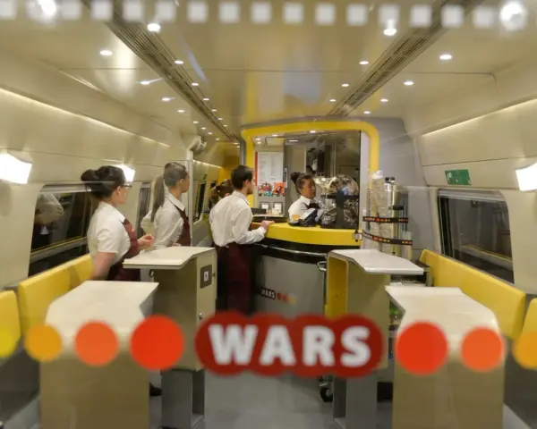 Wnętrze pociągu z personelem obsługującym bar. Widoczny napis "WARS".