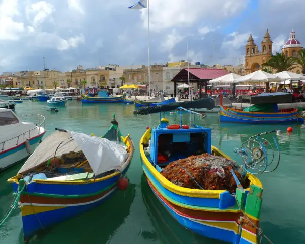 Kolorowe łodzie rybackie w porcie na Malcie, gdzie można poczuć klimat i zobaczyć, jak wygląda malta waluta w codziennym życiu.