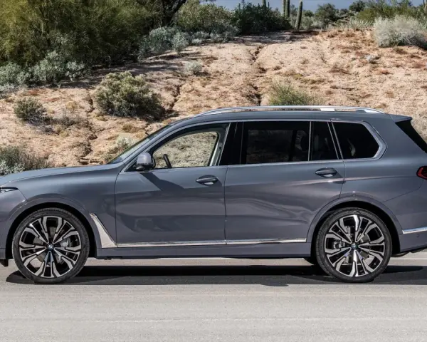 Szary BMW X9 na tle pustynnego krajobrazu. Elegancki SUV z chromowanymi detalami i masywnymi felgami.