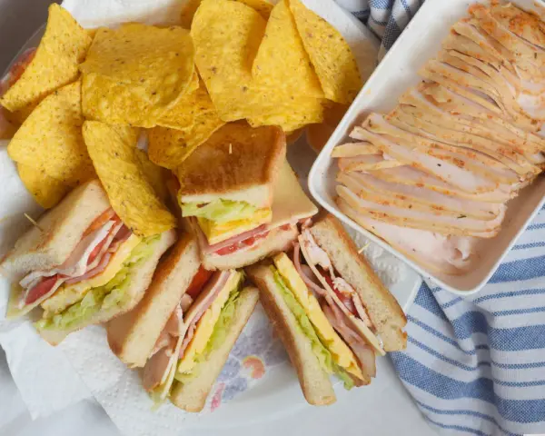 Sandwiches de fiambre de pollo casero, papas fritas y lonchas de pollo. ¡Un festín listo para disfrutar!