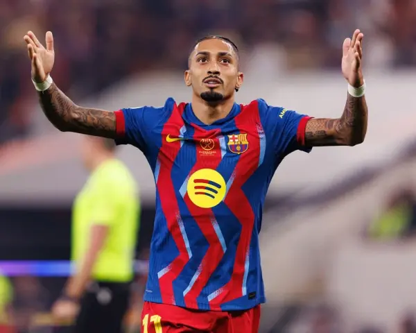 Raphinha, z podniesionymi rękami, świętuje po dołączeniu do FC Barcelony. Jego koszulka zdobi logo Spotify.