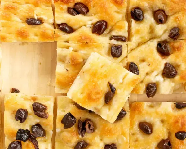 Goldbraune Focaccia mit Oliven, perfekt nach dem original focaccia rezept. Ein Stück ist leicht angehoben.