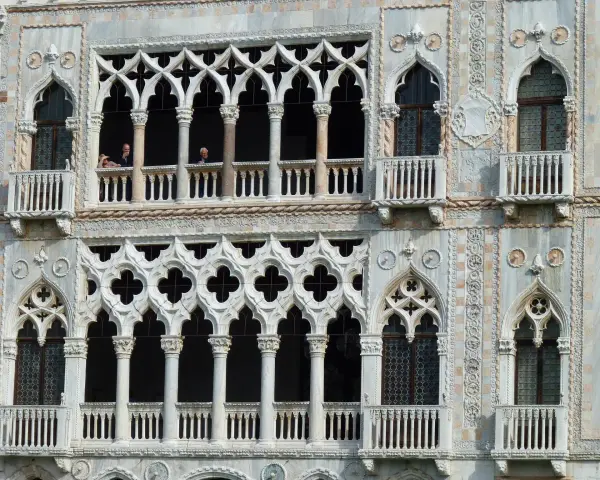 Dettaglio del **Palazzo Cadoro** con le sue finestre a trifora e balconi ornati. Persone osservano dal primo piano.