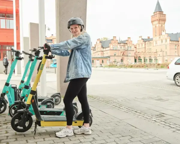 Tjej med hjälm redo att köra elsparkcykel. Tänk på elsparkcykel regler för en trygg resa.