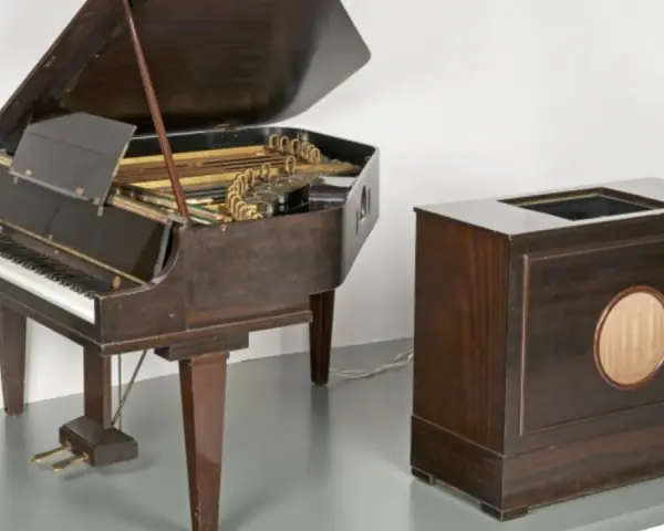 Ein Flügel und ein Holzgehäuse mit Lautsprecher, die zusammen den Beginn des Electronica-Genres markieren.