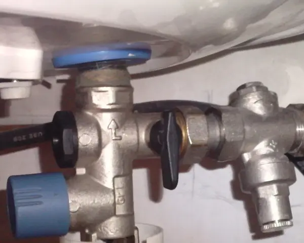 Un réducteur de pression, comme ce dispositif métallique avec une poignée noire, sert à réguler la pression de l'eau dans une installation.