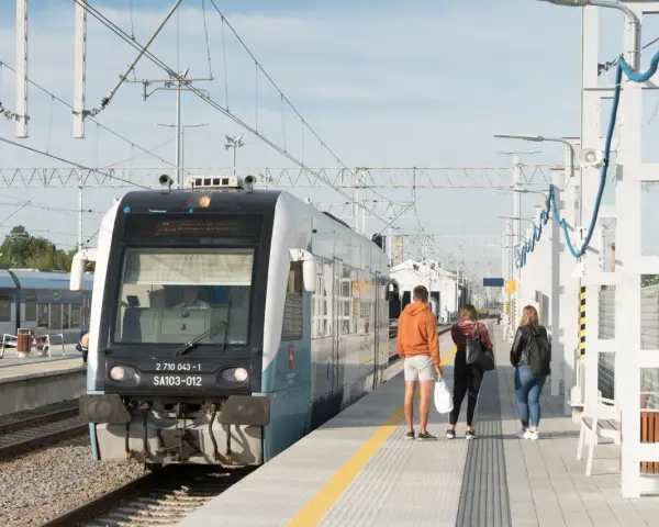 Pociąg na stacji z pasażerami czekającymi na peronie.