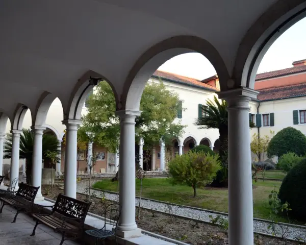 Portico con archi e colonne bianche, panchine e un giardino interno. Per sapere isola degli armeni come arrivare, visita questo luogo tranquillo.