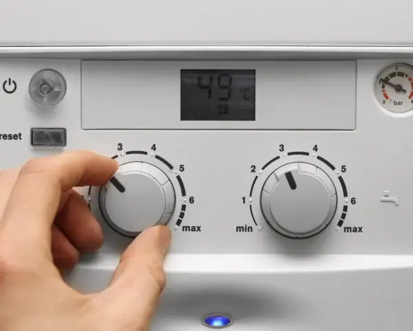 Mano che regola la caldaia spenta senza corrente. Il display mostra 49°C.
