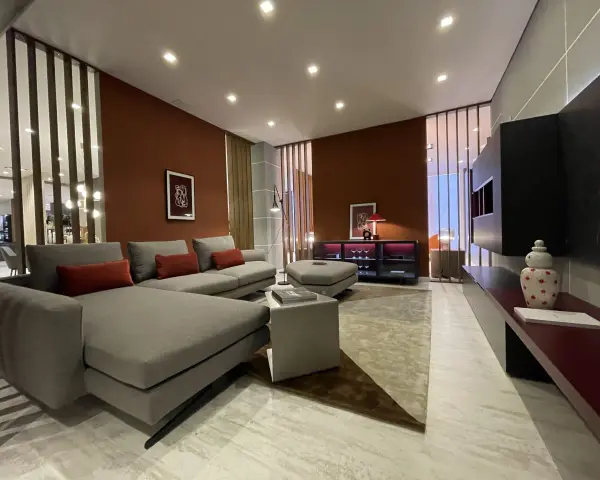Soggiorno moderno con pareti color terracotta e divano grigio. Effetti pittura pareti moderne che creano un'atmosfera calda e accogliente.