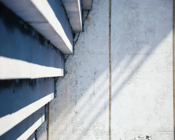 Ombre et lumière sur un mur en béton cellulaire, texture brute et lignes architecturales.