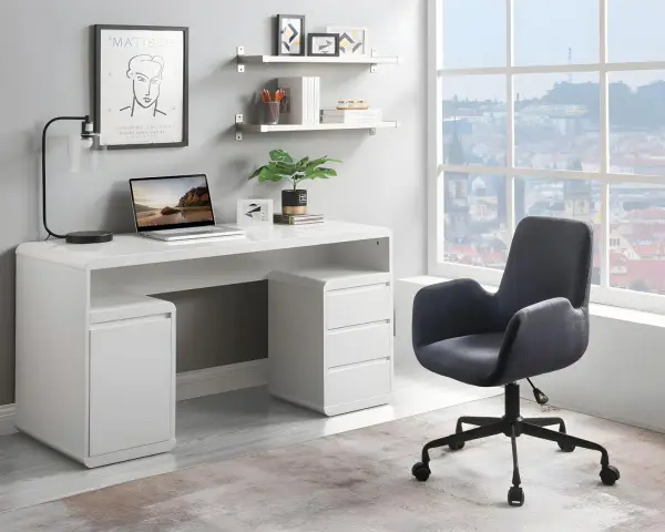 Ett modernt, vitt skrivbord med laptop och lampa utgör ett litet kontor. En bekväm stol står framför ett stort fönster med utsikt över en stad.
