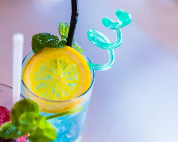 Orzeźwiający drink z sokiem żurawinowym, ozdobiony plasterkiem cytryny i listkami mięty. Idealny na upalne dni.