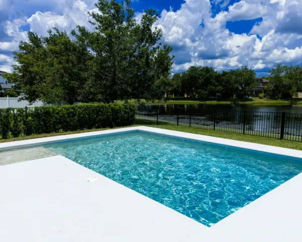 Agua de piscina blanquecina, cristalina y refrescante, con reflejos del cielo azul y nubes blancas. Un oasis de paz.