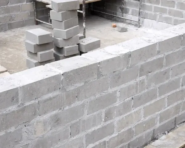Budowa fundamentów z bloczków betonowych, stosy bloczków na placu budowy.