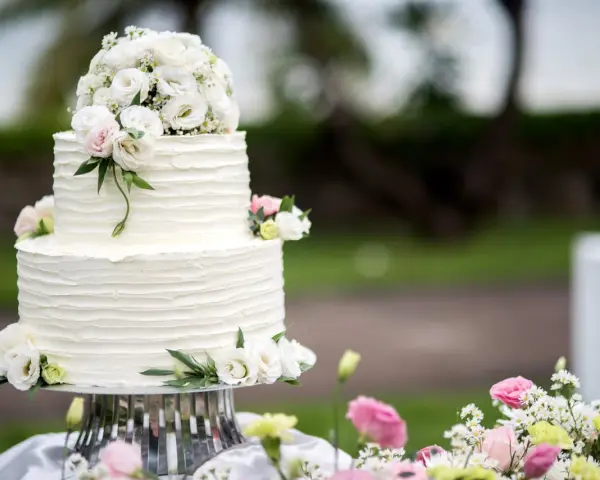 Elegancki, dwupiętrowy tort weselny ozdobiony bukietem białych i różowych, **jakie żywe kwiaty na tort** dodają mu uroku.