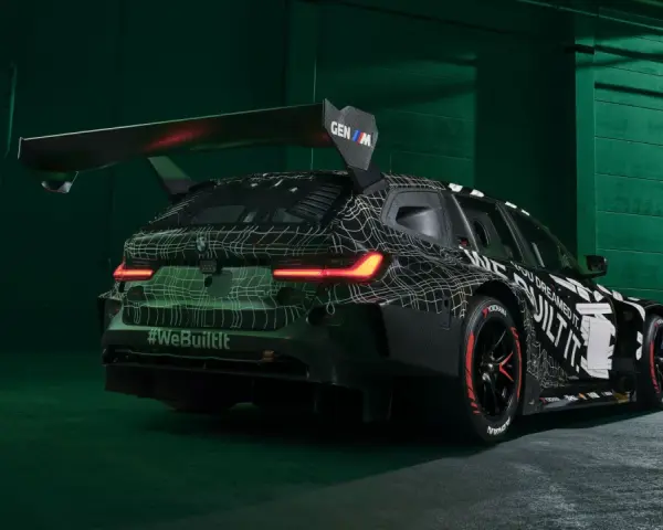 Wyścigowe BMW M3 2025 w kamuflażu, z ogromnym spojlerem i agresywnym dyfuzorem.