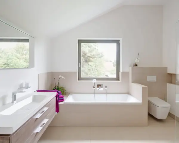Salle de bain moderne avec baignoire, lavabo, douche vitrée et toilette suspendue.