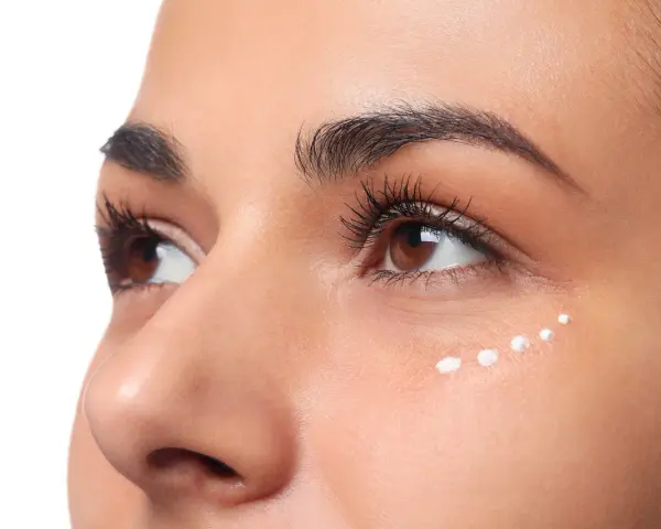 Application de crème hydratante sous les yeux, parfaite pour le maquillage hivernal.