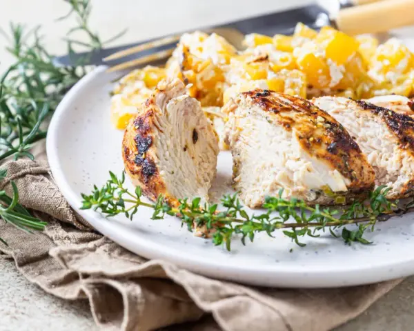 Soczysty indyk z airfryer, pokrojony w plastry, podany z pieczonymi ziemniakami i świeżymi ziołami.