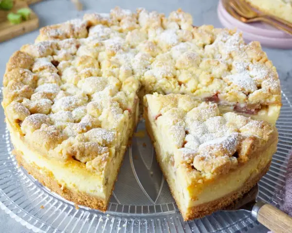 Ein saftiger Rhabarberkuchen mit Puddingfüllung und Streuseln, bestäubt mit Puderzucker.