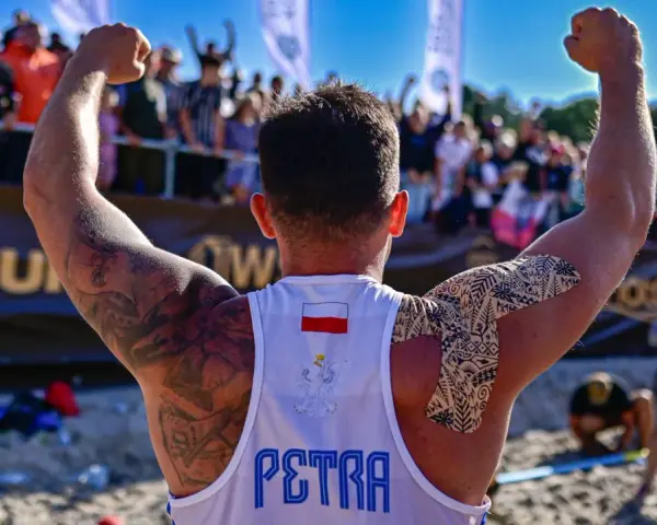 Hubert Wolski, z podniesionymi rękami, świętuje zwycięstwo. Na koszulce widnieje godło Polski i napis "PETRA".