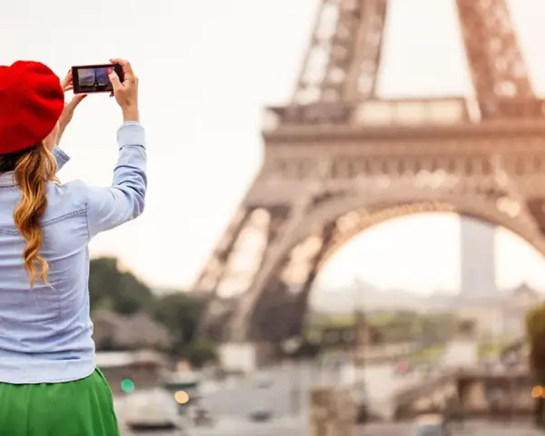Mujer con boina roja toma foto de la Torre Eiffel. ¡Ideas de qué ver en París!