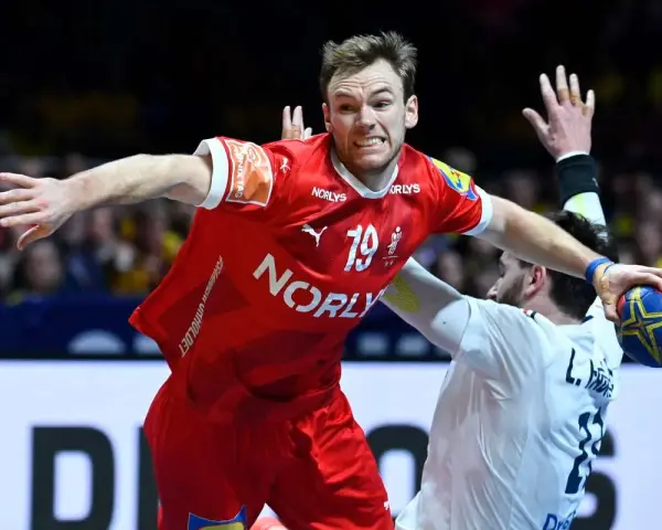 Mathias Gidsel w czerwonej koszulce z numerem 19, w akcji podczas meczu piłki ręcznej, walczy o piłkę.