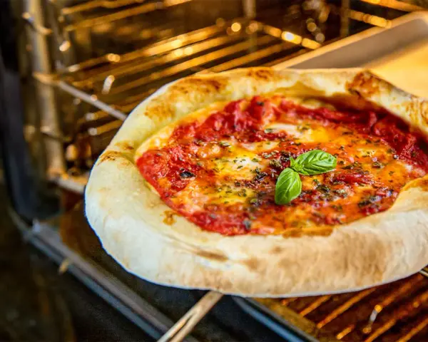 Eine köstliche Pizza im Backofen, mit geschmolzenem Käse und frischem Basilikum.