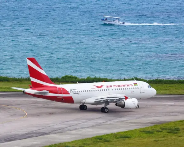 Samolot Air Mauritius na pasie startowym, w tle turkusowe morze i łódź. Twoje loty na Mauritius właśnie się zaczynają!