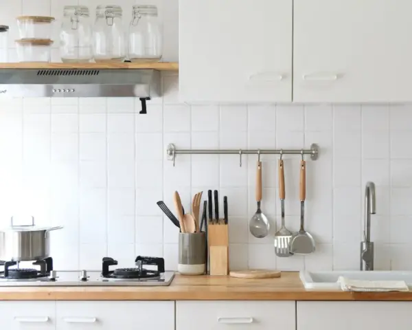 Diseños de cocinas pequeñas y sencillas: encimera de madera, campana extractora, utensilios colgados y un fregadero blanco.