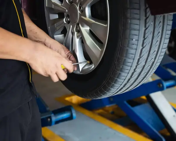 Mechanik sprawdza ciśnienie w oponie. To część usług wulkanizacji, czyli serwisu opon.