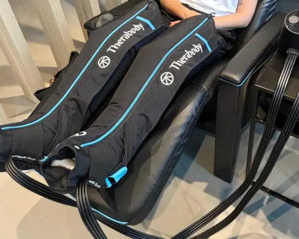 Are leg compression massagers good for you? This image shows a person using Therabody recovery boots, which are leg compression massagers, for a relaxing massage.