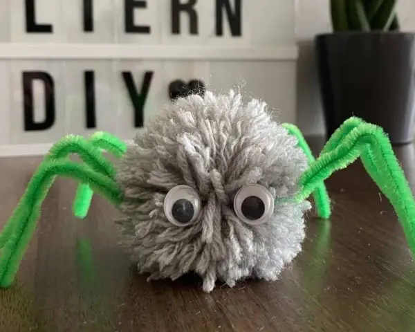 Süße Spinnen-Deko aus Wolle und Pfeifenreinigern, perfekt zum Spinnennetz basteln mit Kindern.