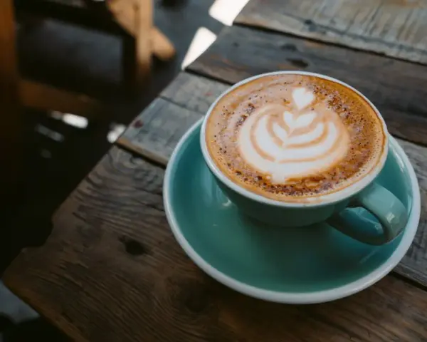 Aromaticzna kawa ristretto z pianką latte art na drewnianym blacie. Idealny poranek.