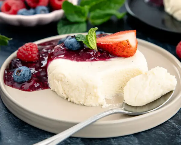 Cremige bayrische Creme mit Beerensoße, Erdbeere und Minze. Ein Löffel voller Genuss.