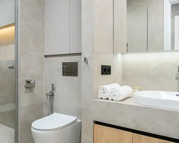Modernt kaklat badrum med dusch, toalett och handfat. Ljus och stilren design.