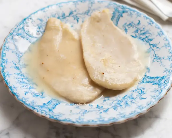 Delicate scaloppine al vino bianco, servite su un piatto decorato con motivi blu.