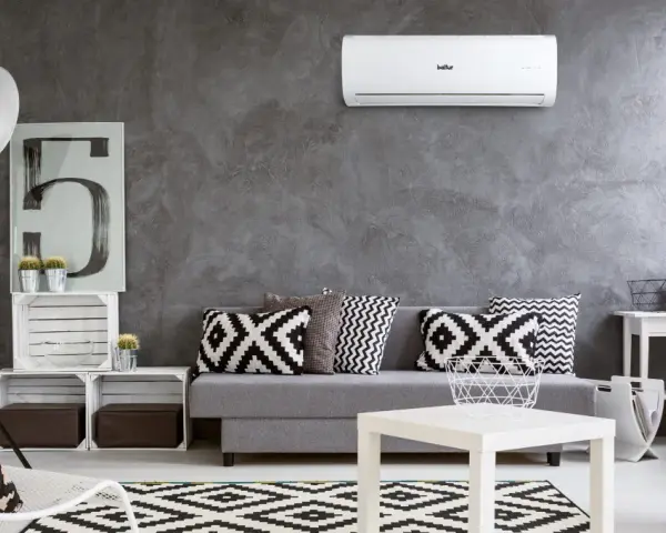 Un moderno soggiorno con divano grigio, cuscini geometrici e un **condizionatore** a parete. Il significato è comfort e stile.