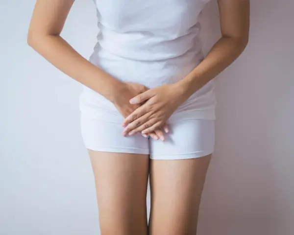 Kobieta w białej bieliźnie, dłonie zasłaniające krocze. Może symbolizować żółte upławy w okresie menopauzy.