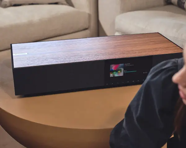 Elegancki Cambridge Audio One z drewnianym blatem i ekranem odtwarza muzykę.