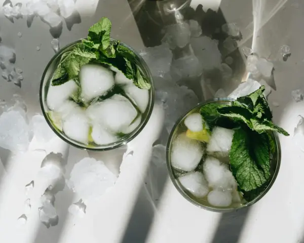 Dwa orzeźwiające augustowskie mojito z lodem i miętą, otoczone pokruszonym lodem.